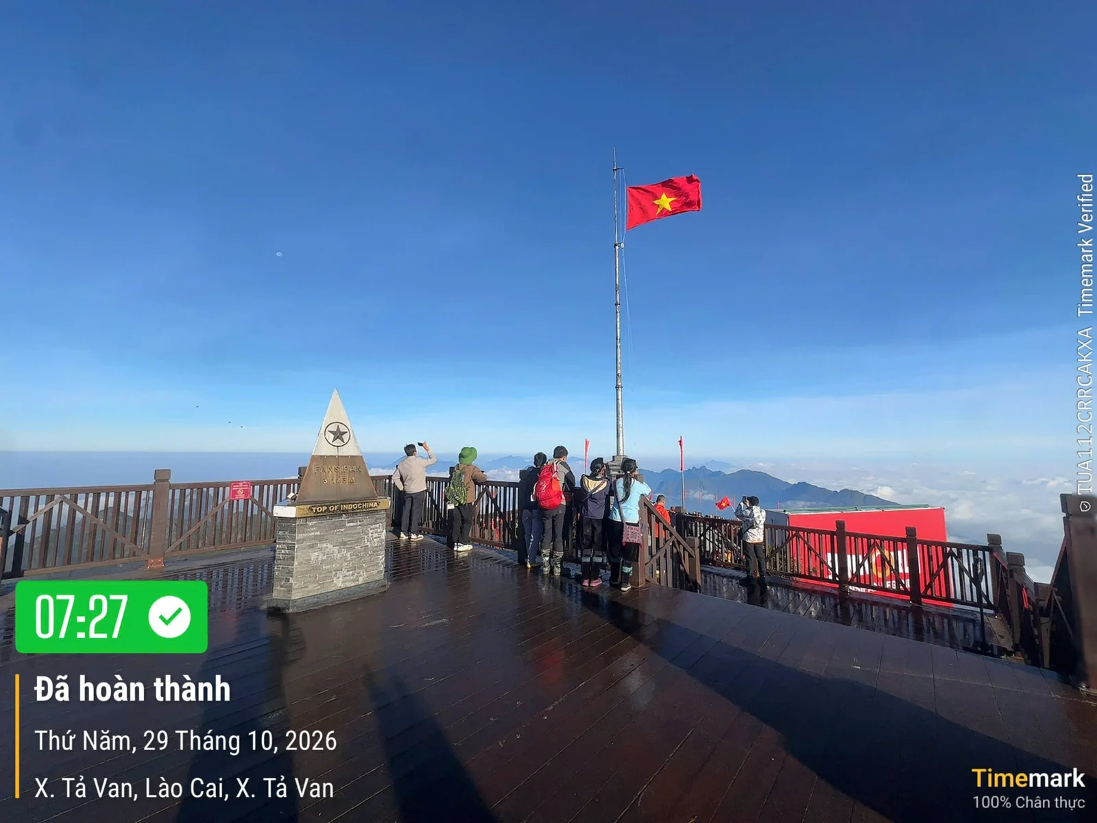 Du khách ngắm cảnh trên đỉnh Fansipan lúc 07:27 ngày 29/10/2026: du khách bên cột mốc và cột cờ, phía sau là núi và biển mây